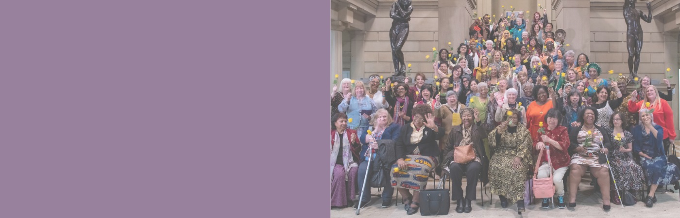 Diverse group of women posing with yellow roses at Manchester Art Gallery.