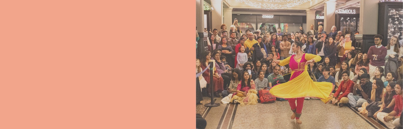 A woman dancing in traditional Indian dress for a crowd of people.